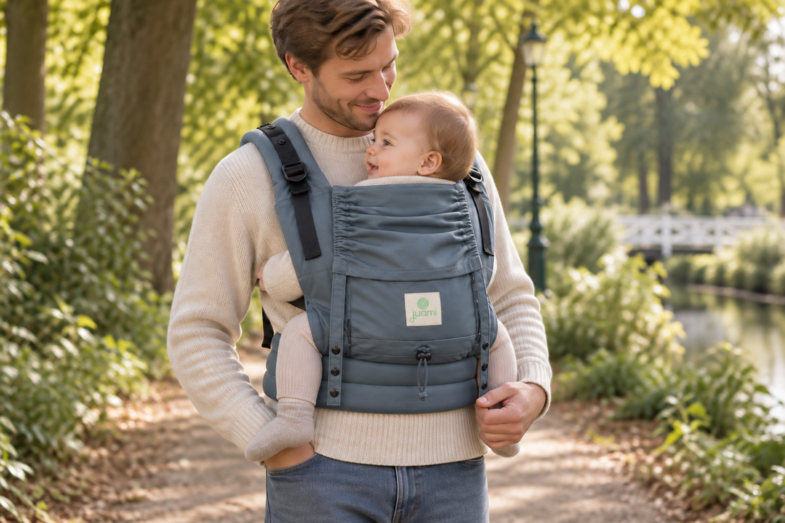 Vader draagt zijn baby in een blauwgrijze draagzak tijdens een wandeling in het park.