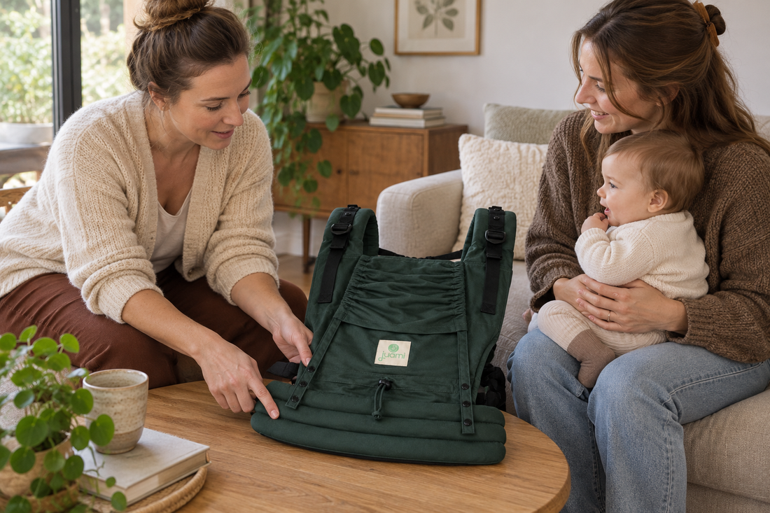 Moeder met baby op schoot bespreekt een groene draagzak met een draagconsulente.