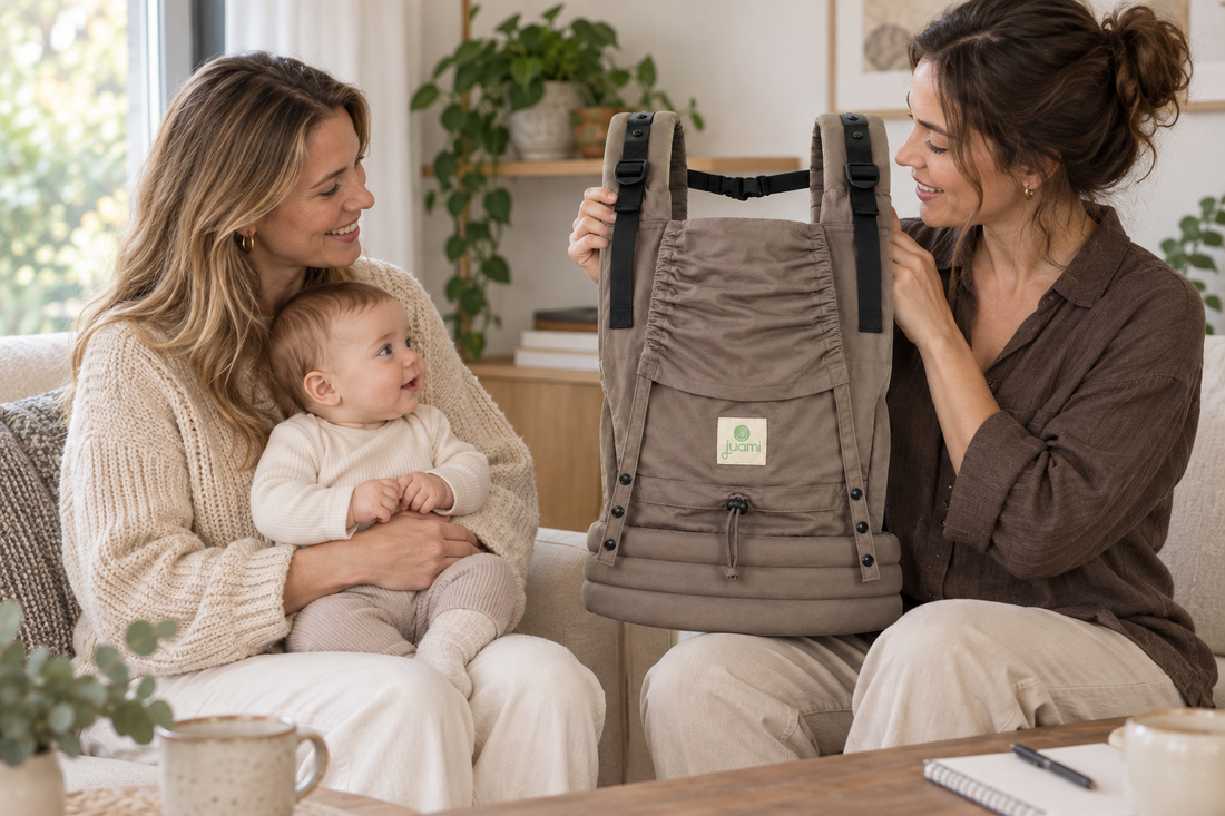 Draagconsulente toont de brede heupband van een taupekleurige draagzak aan een ouder met baby.