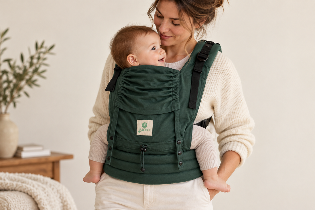 Moeder draagt haar baby naar zich toe in een groene draagzak, met de beentjes aan weerszijden.