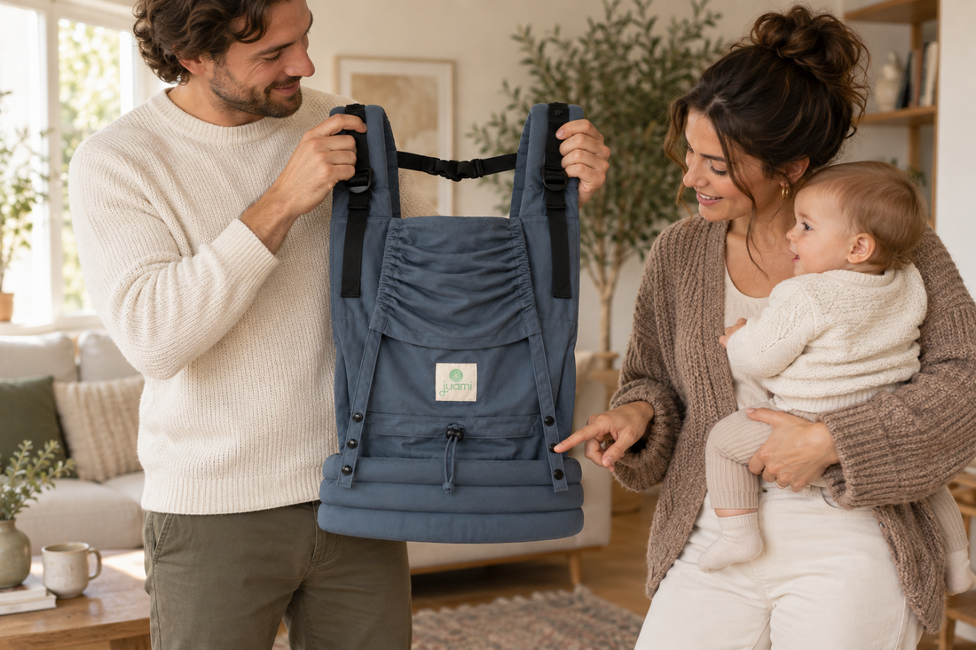 Ouders bekijken de verstelbare banden van een blauwgrijze draagzak terwijl moeder de baby vasthoudt.