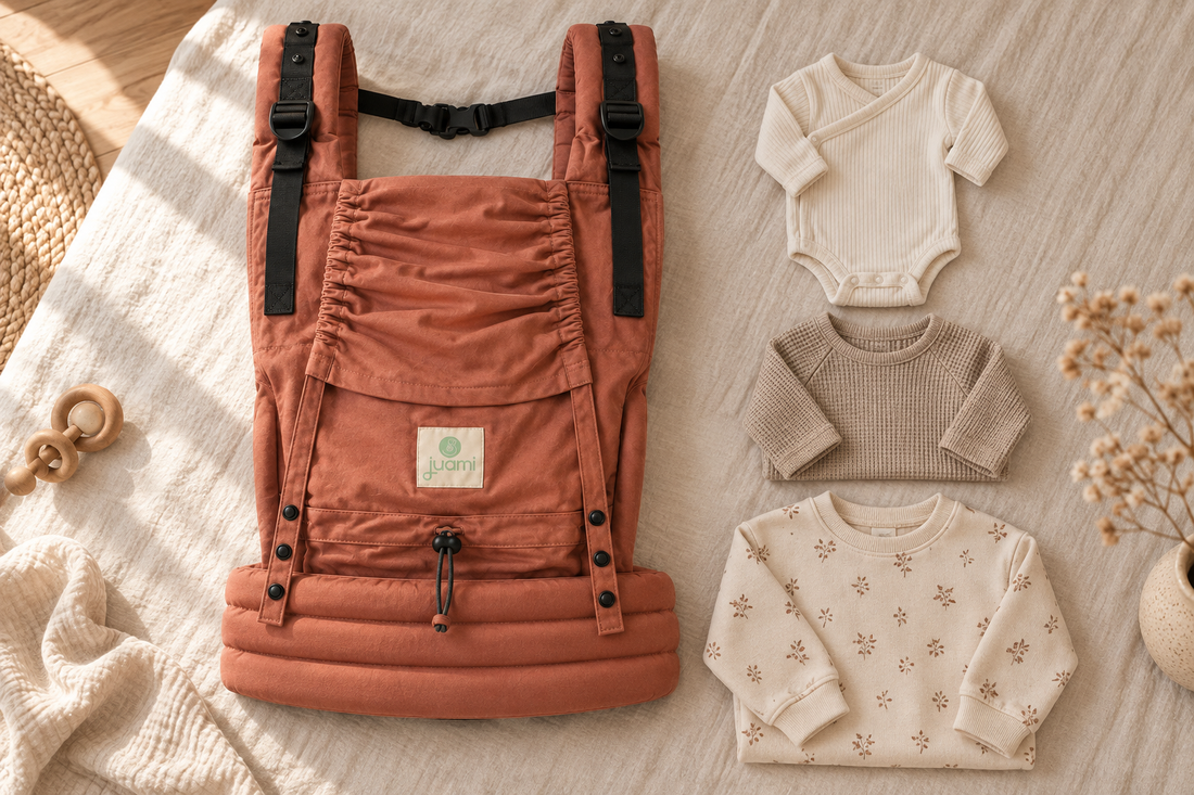 Terracotta draagzak naast babykleding in verschillende maten op een lichte ondergrond.