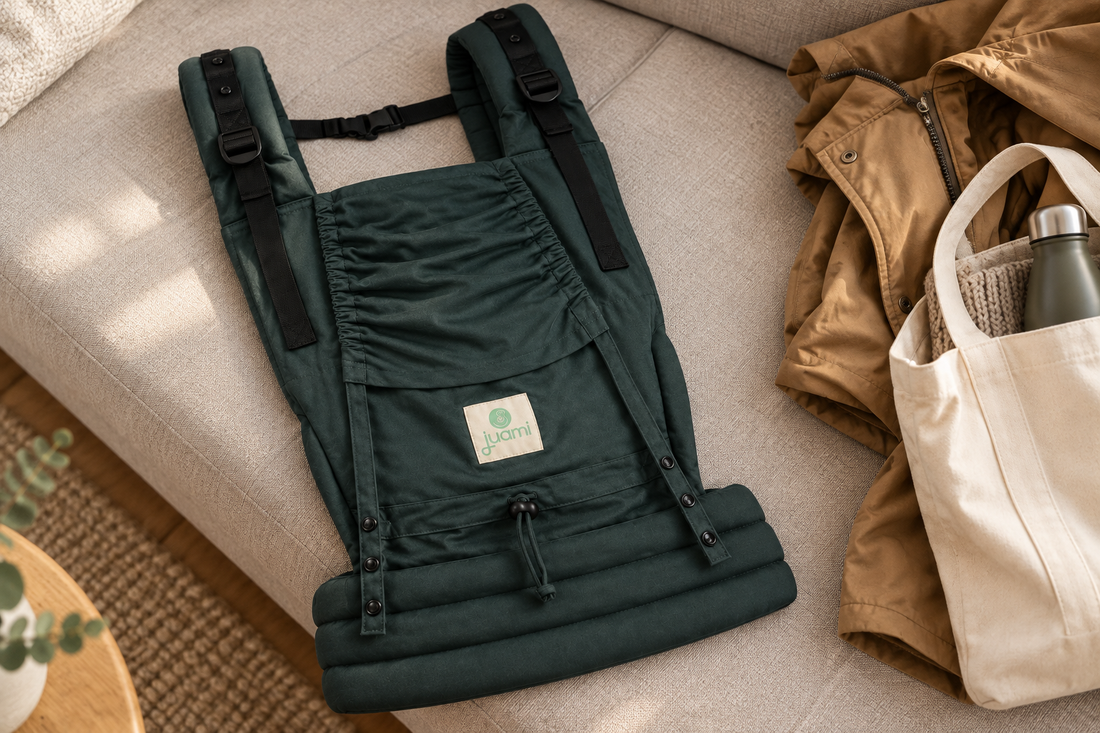 Groene Juami EasyGrow draagzak op een lichte bank naast een jas en tas, klaar voor een wandeling.