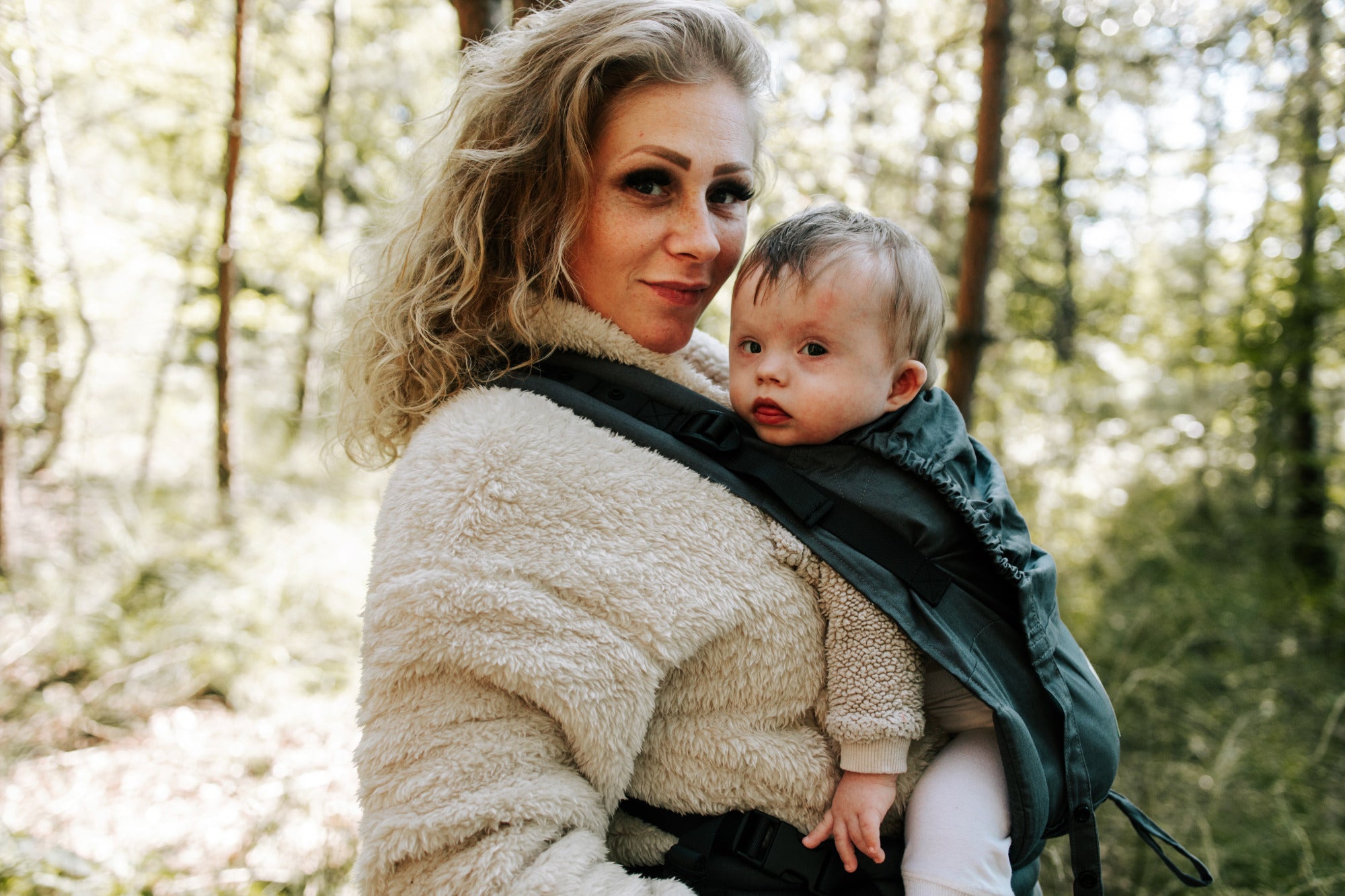 Moeder en baby genieten samen van een wandeling in de natuur met de ergonomische draagzak van Juami.